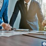 2 человека за столом, разбирающие документы