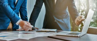 2 человека за столом, разбирающие документы