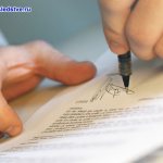 A man puts his signature on a document