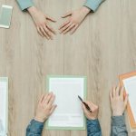 people&#39;s hands on the table and documents