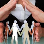 Руки мужчины и женщины, защищающие бумажных человечков