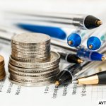 Stacks of coins and several pens lying on the table